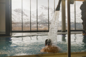 France, Le Devoluy, 2022-03-15. Man from behind under water jet in the large bath of the Odycea wellness centre. The 140